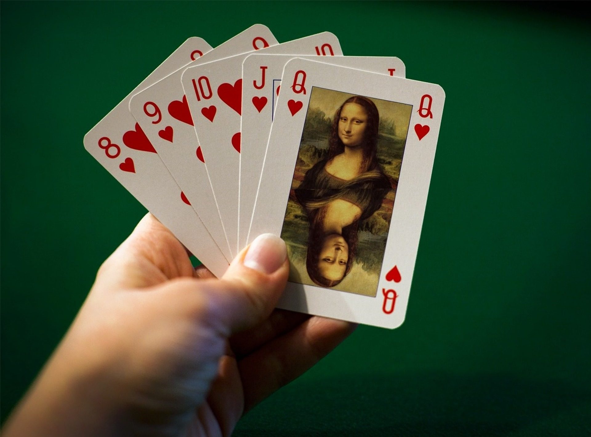 Eine Hand hält 5 Spielkarten mit Herz8, Herz9, Herz10, HerzJ, HerzQ. Auf der Herz Q befindet sich ein Bild von Mona Lisa.